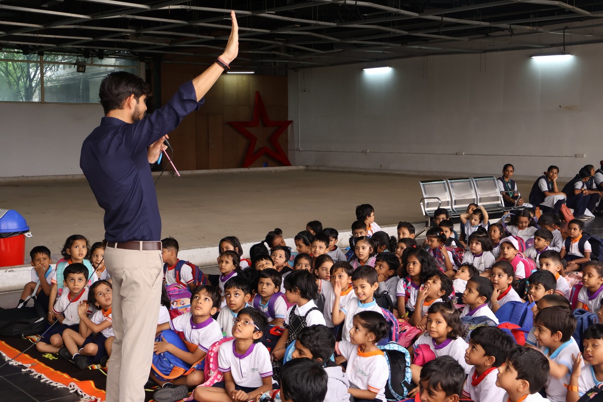 A facilitator addressing a hall of children and teachers