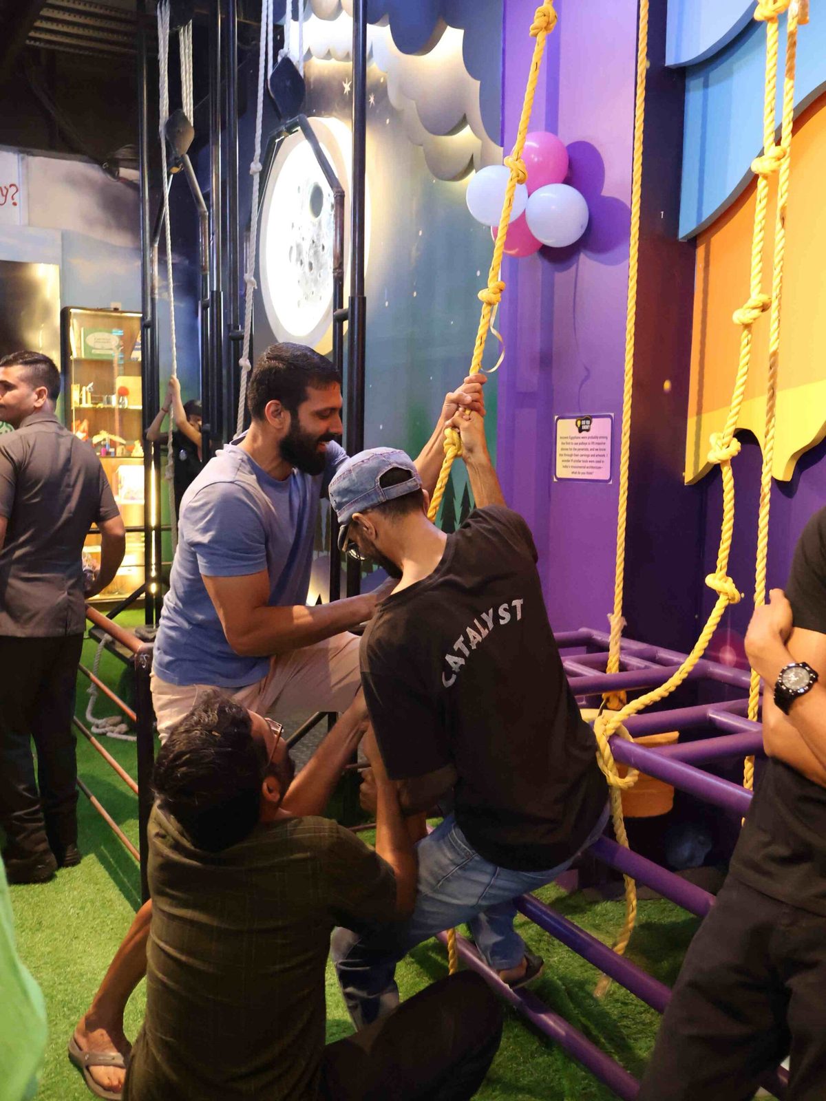 Visitors hauling on the ropes of the cosmic lift to hoist a seated rider