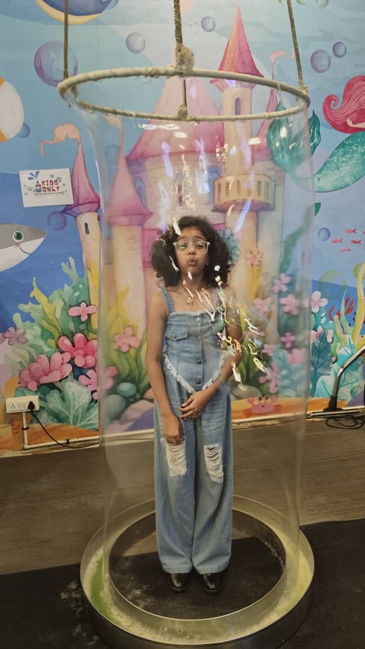A girl standing inside a giant soap bubble ring being pulled up around her