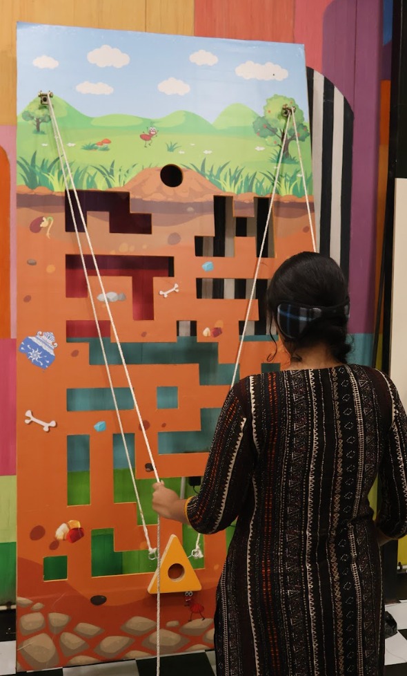 A visitor hauling on the ropes of the pulley wall at Madlabs