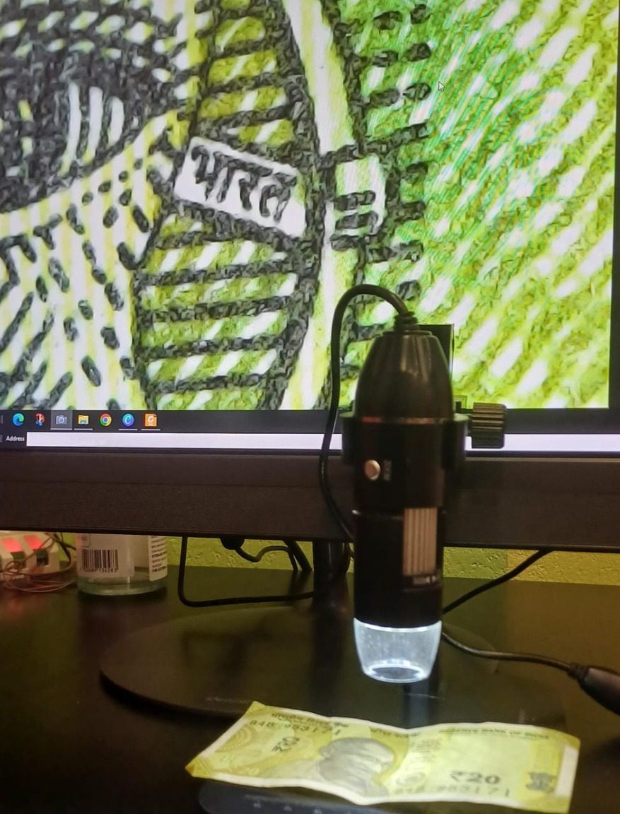 A digital microscope at a workstation projecting a live specimen onto the screen