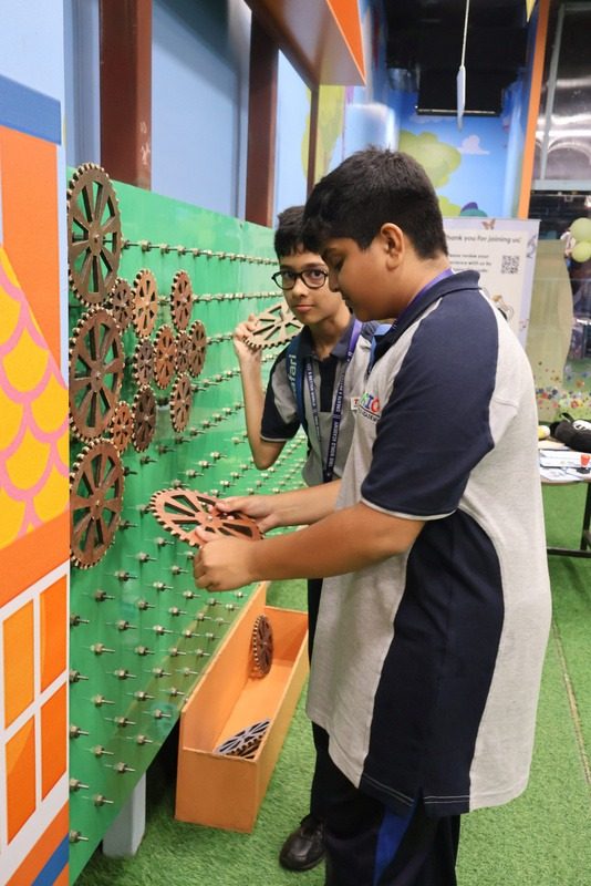 A boy and a facilitator working together at a green pegboard wall